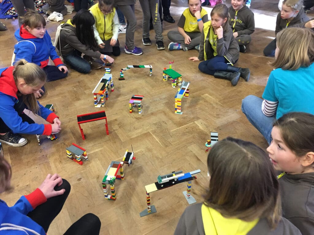 Guides, brownies and rangers gathered round different model bridges made of Lego